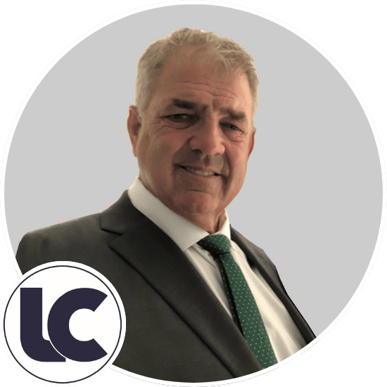 Man in suit with green tie smiling, set against a gray background. Circular logo with "LC" in the corner, possibly related to concrete.