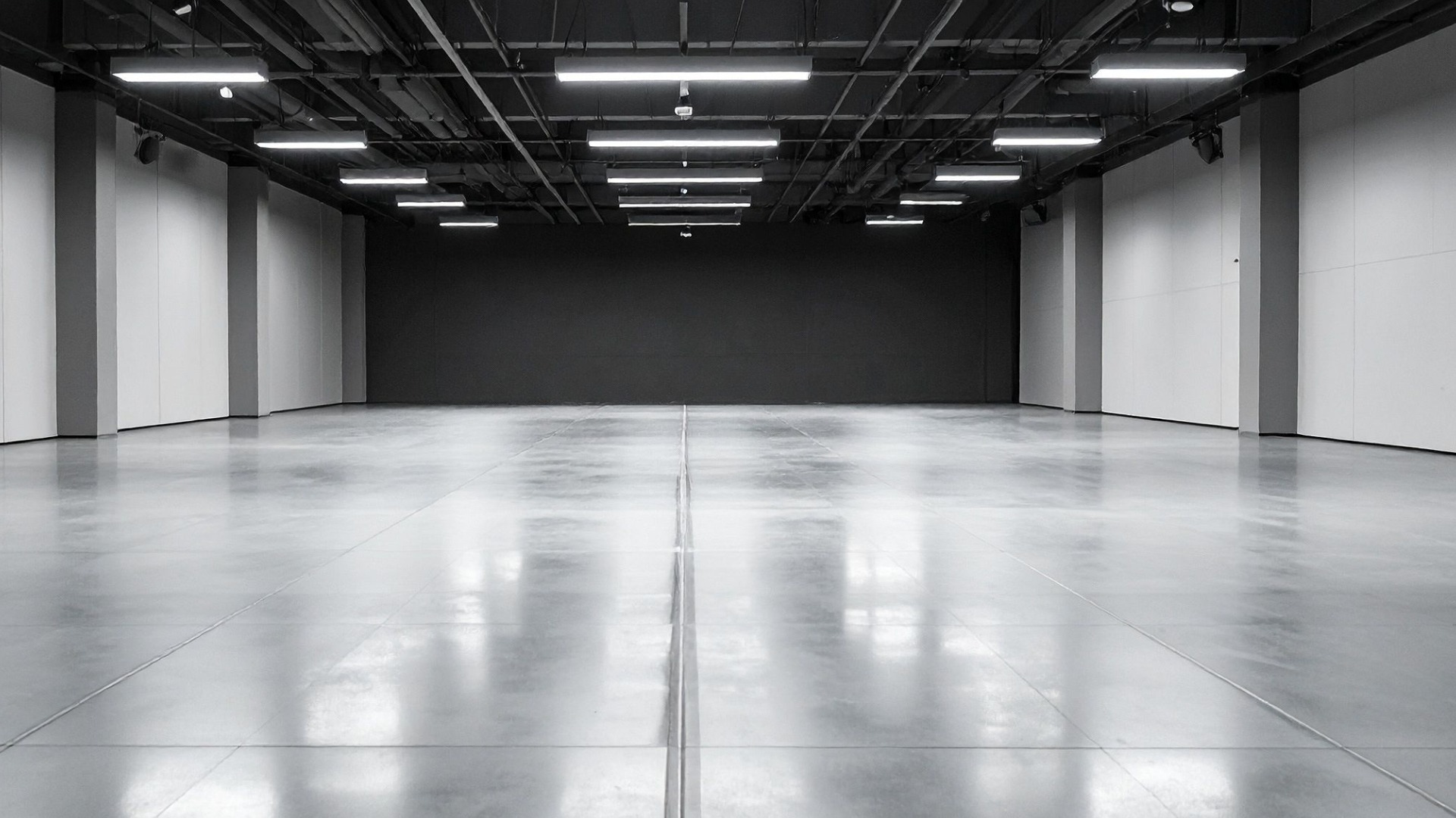 Spacious hall with polished concrete floor, dark ceiling, and bright overhead lighting.