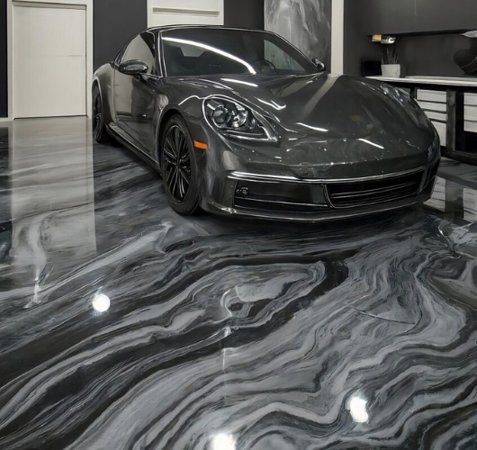 Sleek gray sports car parked on a polished, marble-like concrete floor in a modern showroom.