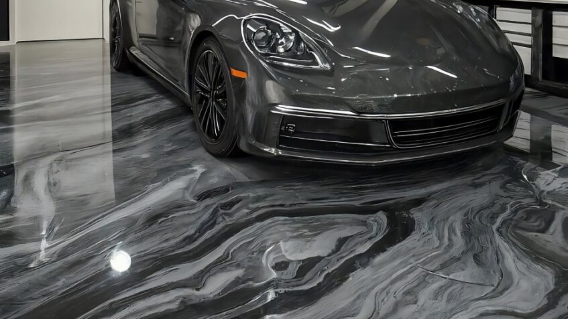 Sleek gray car parked on polished, marbled concrete floor with swirling black and gray patterns.