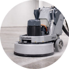 Floor grinding machine smoothing concrete surface, featuring prominent circular base, industrial wheels, and a sleek design for efficient operation.