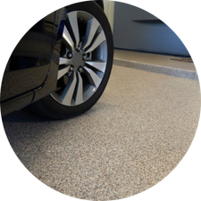 Car wheel parked on a speckled concrete floor, next to a raised platform, highlighting garage setting.