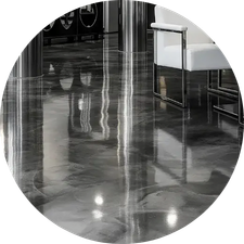 Polished concrete floor with reflective sheen, white chair with metal frame in background, and shiny pillars.