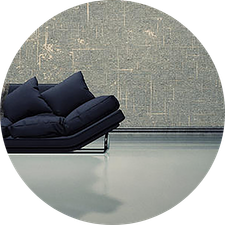 Modern room with gray textured wall, sleek dark sofa, and smooth concrete floor.